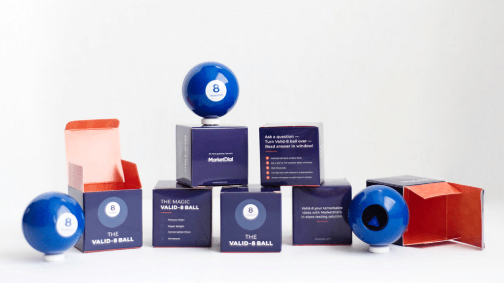 Multiple Marketdial branded magic 8 ball, sitting next to well-designed boxes made for holding the magic 8 balls.