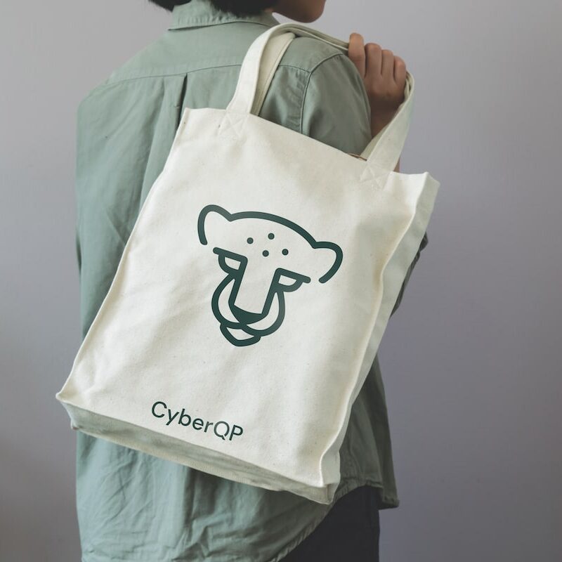 Woman holding shoulder bag printed with CyberQP logo